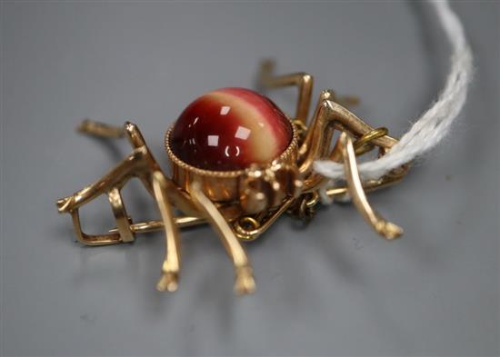 A yellow metal and chatoyant cabochon gem set spider brooch, 35mm, gross 10 grams.